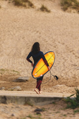 Surfer with Orange Surfboard Walking on Sandy Beach.