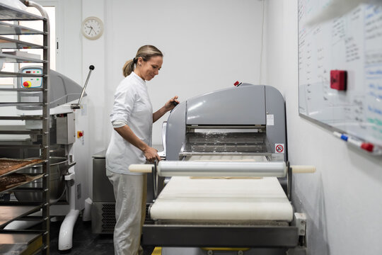 Pastry chef operating dough sheeter in bakery