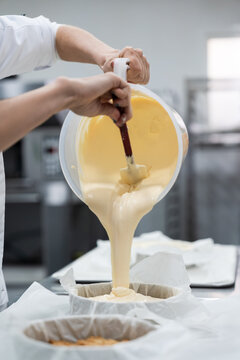 Pastry chef pouring batter into cake pans