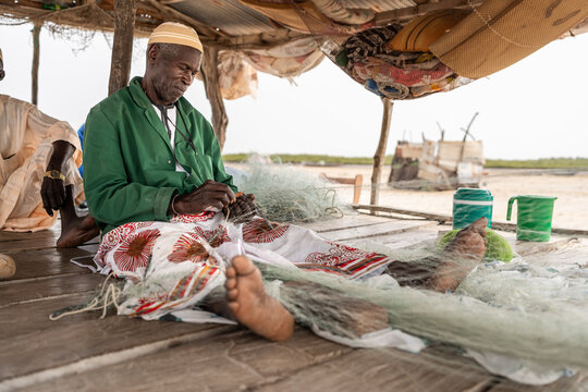 Fisher repairing nets on senegal shore
