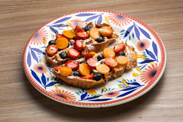 French toast in honey and with fresh fruits, strawberries, cape gooseberries and blueberries