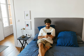 Man in casual clothes enjoying leisure time in bedroom