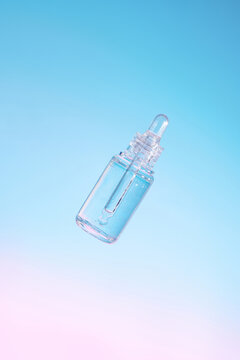 Transparent dropper glass bottle flying in antigravity on gradient