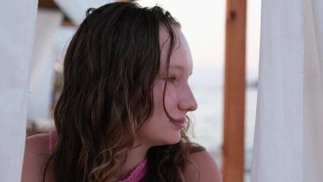 Thinking Girl in pink dress Seated On the Beach near the sea. Girl on the beach in a pink dress