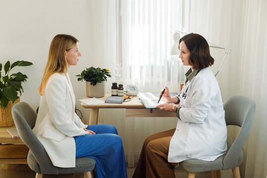 Female doctor in a white coat counsels a young woman