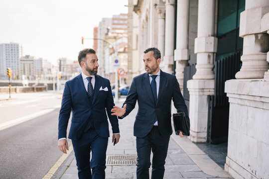 Businessmen Walking and Talking Outdoors - Powered by Adobe