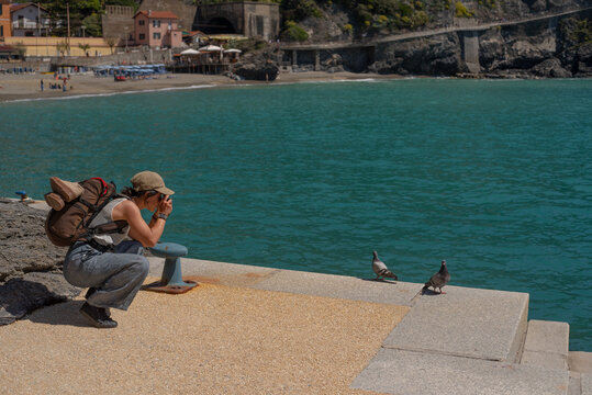Tourist photographing pigeons by the sea