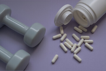 A bottle of weight loss pills with gymnastic dumbbells