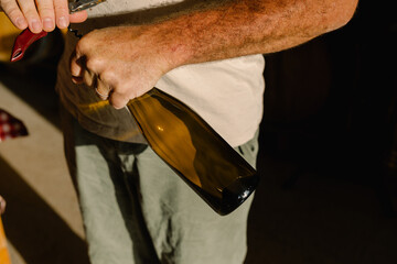 Unidentified man open a bottle of organic wine inside a small winery