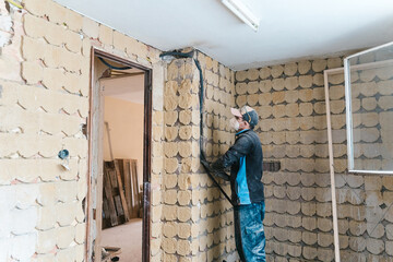 Busy electrician mounting conduit cable on brick wall