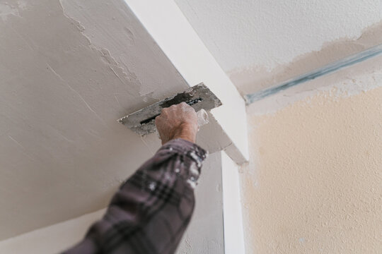 Crop man plastering wall with putty paint