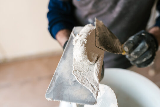Crop carpenter putting plaster on trowel