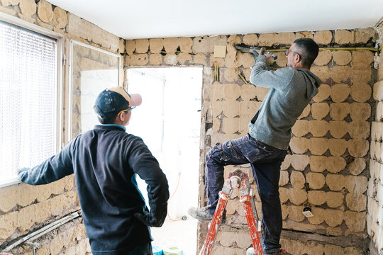 Concentrated repairman with chisel working on brick wall