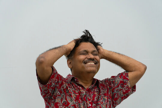 A middle aged Indian man enjoying rain in a hot summer day