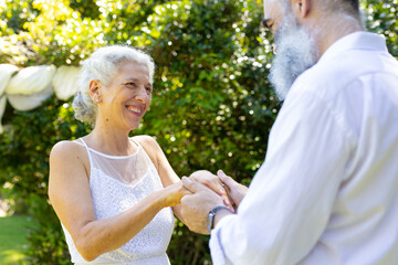 Smiling senior bride holding hands with groom at outdoor wedding