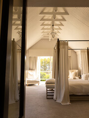 Elegant bedroom with canopy bed and cozy armchair, sunlight streaming in, copy space