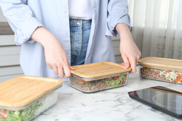 Healthy food. Woman closing glass container with meal at white marble table, closeup