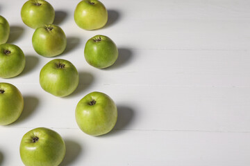 Fresh ripe green apples on white wooden table. Space for text