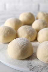 Many raw dough balls with flour on table