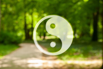 Yin and yang symbol against blurred view of green park