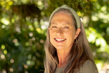 Smiling mature woman with long hair and headband enjoying outdoor nature