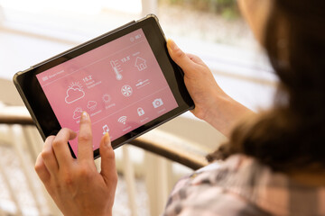 Using tablet, woman controlling smart home system for temperature and security