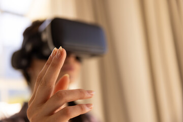 Using VR headset, woman interacting with virtual environment at home