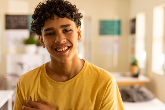 Smiling teenage boy in high school classroom, wearing yellow shirt and looking happy - Powered by Adobe