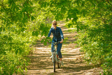 Fototapeta premium beautiful blonde rides a bike in the forest