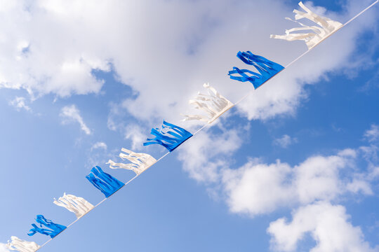Blue And White Flags Against Cloudy Blue Sky.
