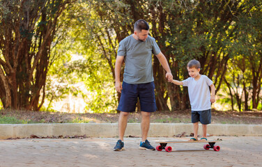 A happy Brazilian father helps his son balance on a skateboard in the street. The image captures moments of the father supporting and teaching his son
