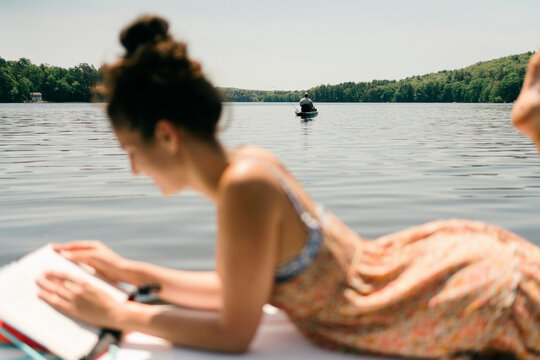 young woman reading. book on paddle board 
