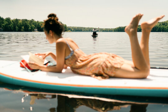 young woman reading. book on paddle board 