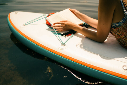 young woman relaxing and reading. on paddle board 