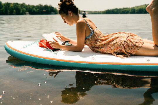 young woman relaxing and reading. on paddle board 