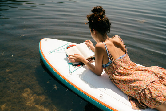 young woman relaxing and reading. on paddle board 