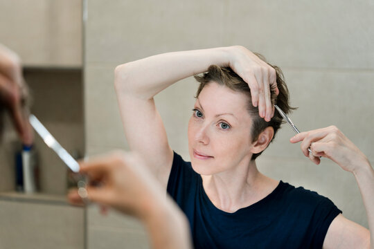 Woman cutting hair in mirror