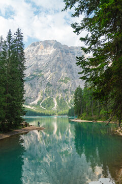Man walking on Lago di Braies lake in Dolomites in summer 