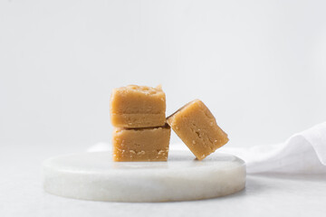 peanut butter fudge on a marble tray, soft peanut fudge squares stacked on a white tray