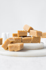 peanut butter fudge on a marble tray, soft peanut fudge squares  stacked on a white tray