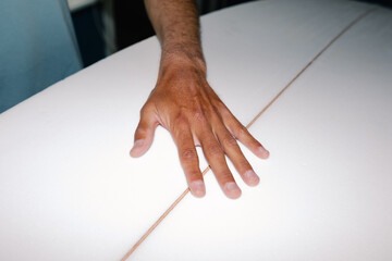 Surfer inspecting the quality of a surfboard in a shaping room