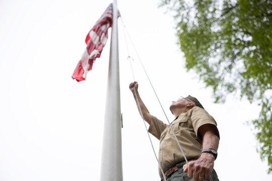 Senior Citizen military War Veteran Raising American Flag at flagpole 