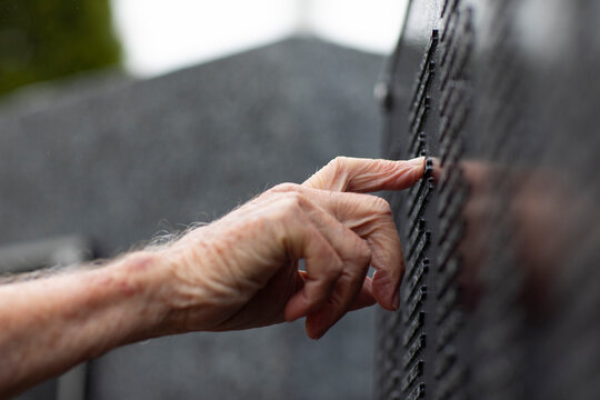 Hand careful touching name of Fallen Soldier at war memorial 