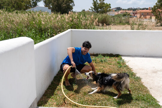 Joyful moment of man playing with dog using hose