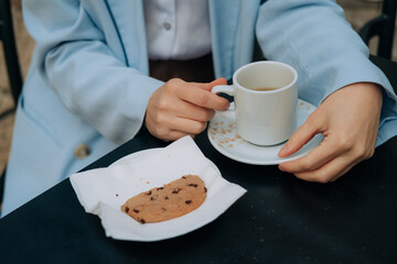 Anonymous woman with a cup of coffee and a cookie 