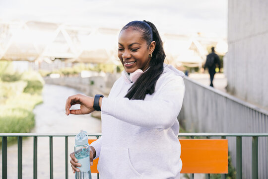 Curvy Dominican woman checks fitness tracker in urban park