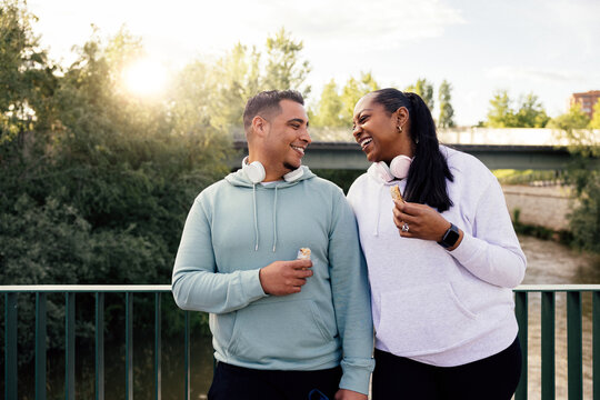 Curvy Dominican couple enjoying energy chocolate bar in the park