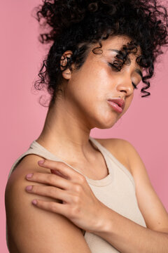 woman with curly hair touching her shoulder