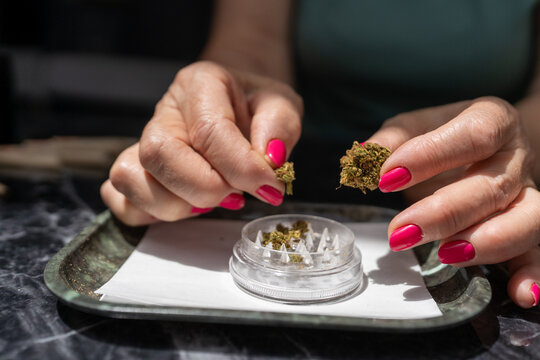 Hands Positioning Cannabis Bud on Grinder.