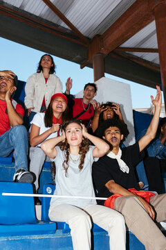 Excited sports fans cheering in stadium bleachers